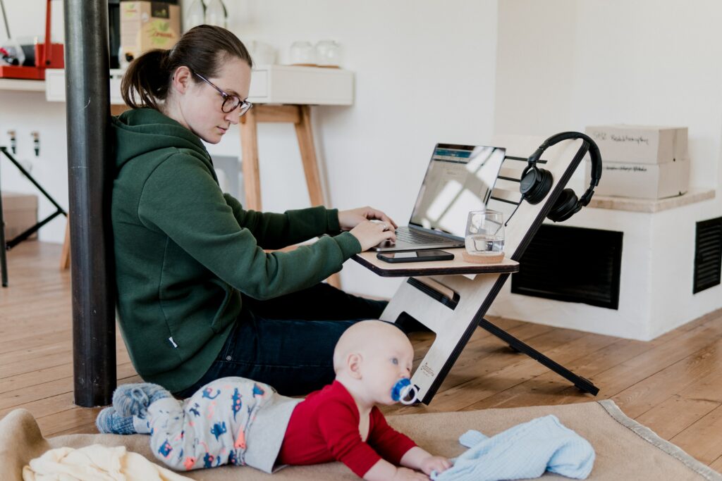 Woman working from home while looking after her child