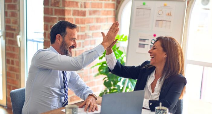 Photo of two people high-fiving for a Kambu blog article about the relationship between HR and IT